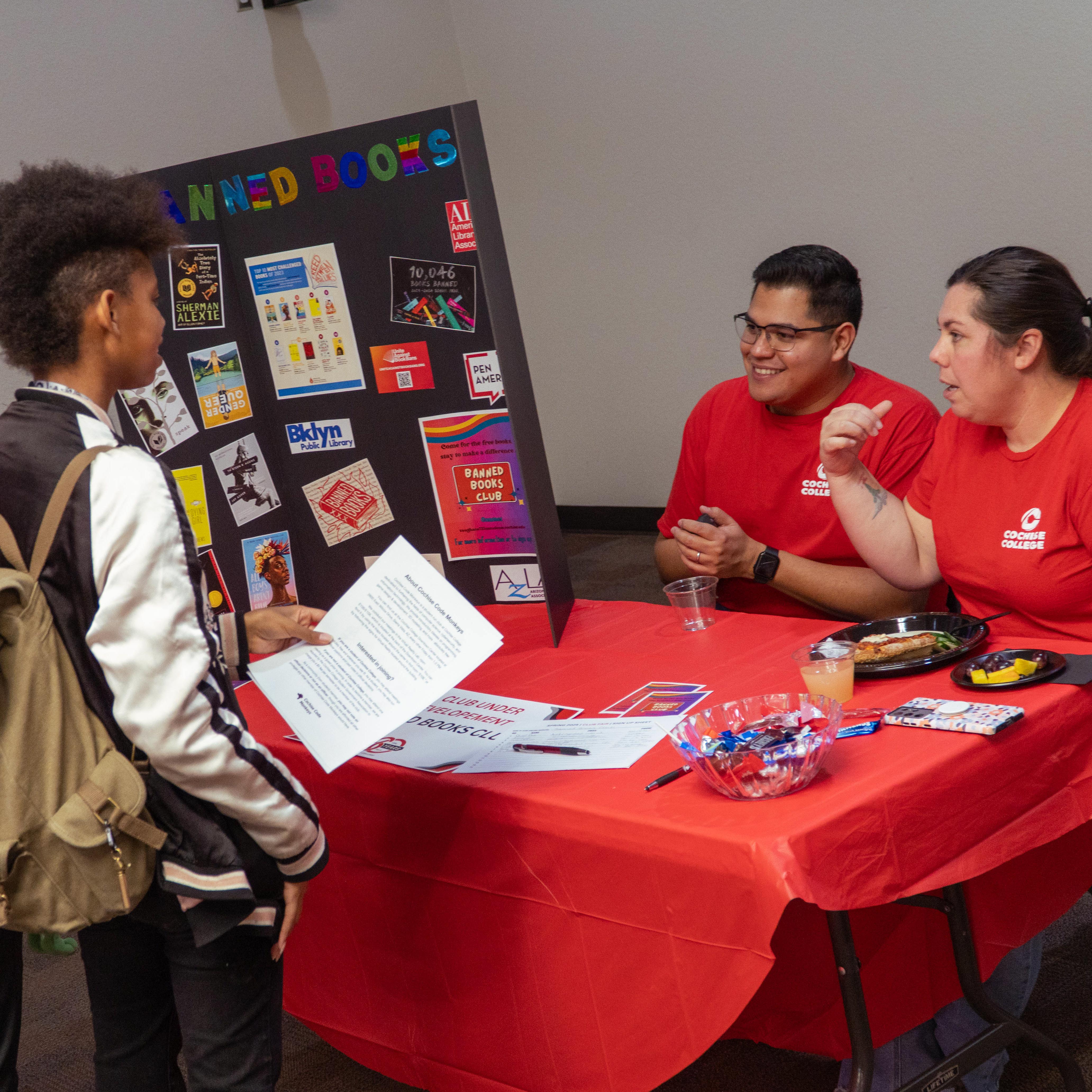Students at club fair booth with staff
