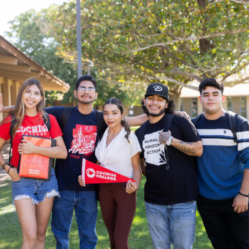 Group of Cochise College students smiling outdoors on Douglas campus, holding school gear and enjoying a sunny day.